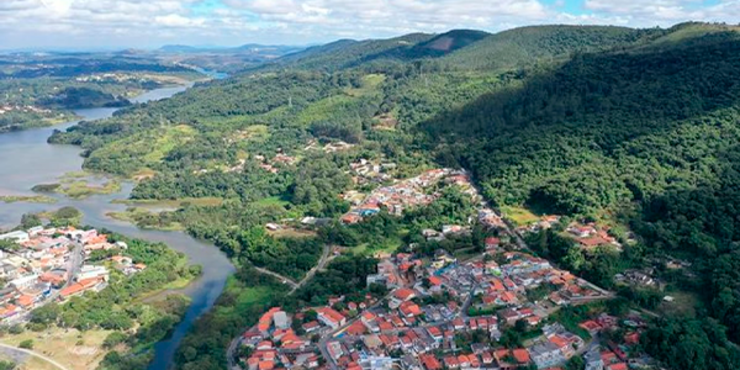 Imagem de cidade pequena cerca de morros e um rio, em dia claro