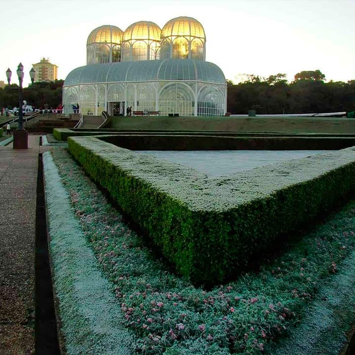Imagem do Orquidário de Curitiba, uma estrutura de vidro única com design futurista e jardins bem cuidados ao redor, localizado em Curitiba, Brasil.
