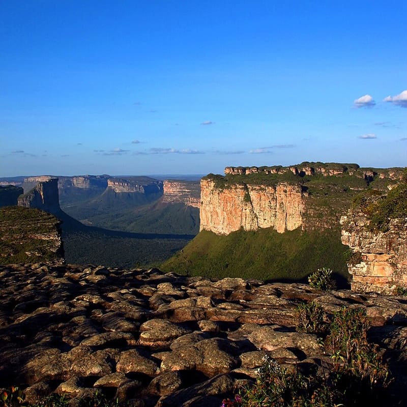 Vista panorâmica do Parque Nacional da Chapada Diamantina na Bahia, Brasil, mostrando cachoeiras, vales e maciços rochosos sob céu azul claro.